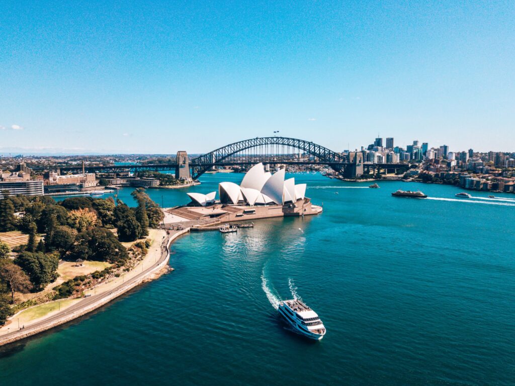 Sydney Harbour with the iconic Sydney Opera House and Harbour Bridge, featuring a boat on the water and a clear blue sky, highlighting Australia's financial landscape and mortgage options.