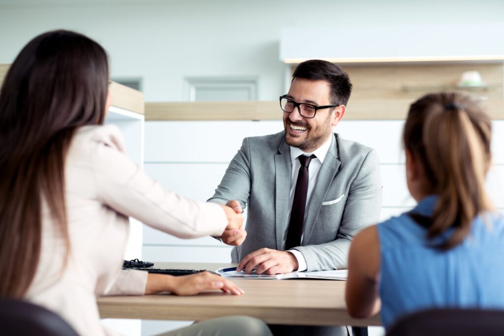 Professional financial advisor shaking hands with clients in a modern office setting, illustrating home loan consultations for casual workers and tradies.