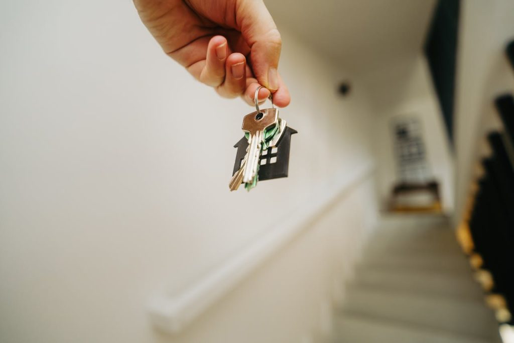 Hand holding house-shaped keychain with keys, symbolising securing a first home loan and navigating house financing options.