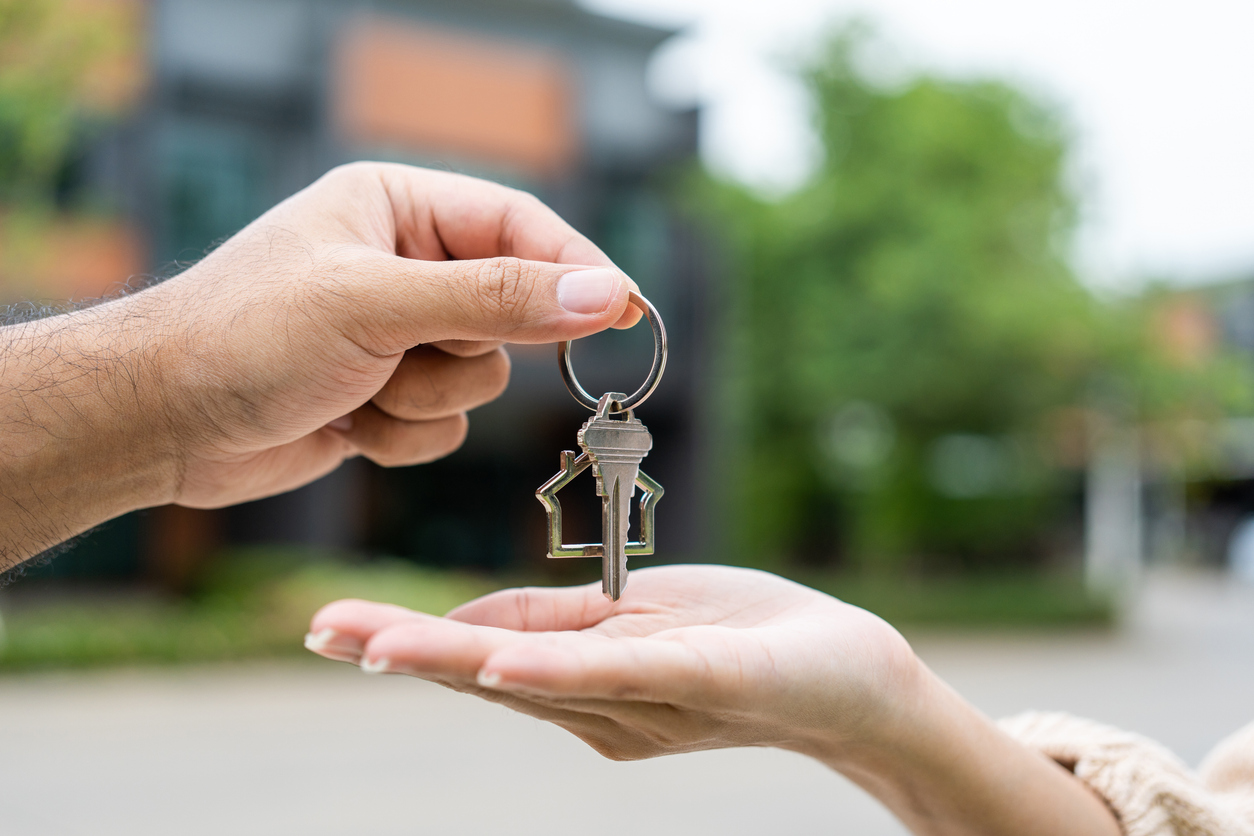Hand passing house keys to another person, symbolizing home ownership and the process of securing a home loan in Sydney.