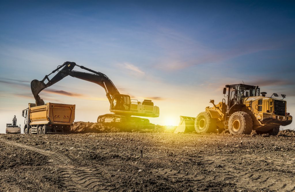 Excavator and construction vehicles on a building site at sunset, representing the construction sector relevant to business loans in New South Wales.