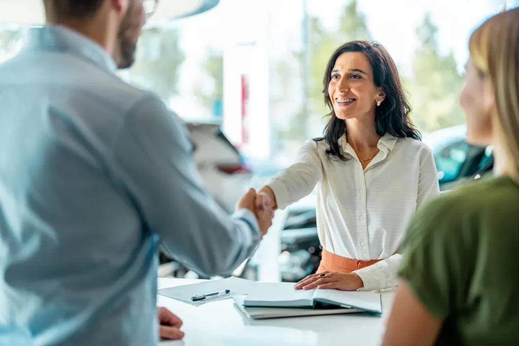 Smiling financial consultant shaking hands with clients in a modern office, representing asset financing and refinancing solutions in Sydney.