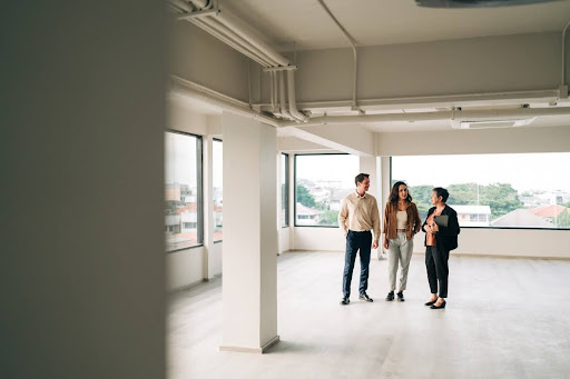 Three professionals discussing in an empty commercial property space, highlighting the potential for refinancing opportunities.