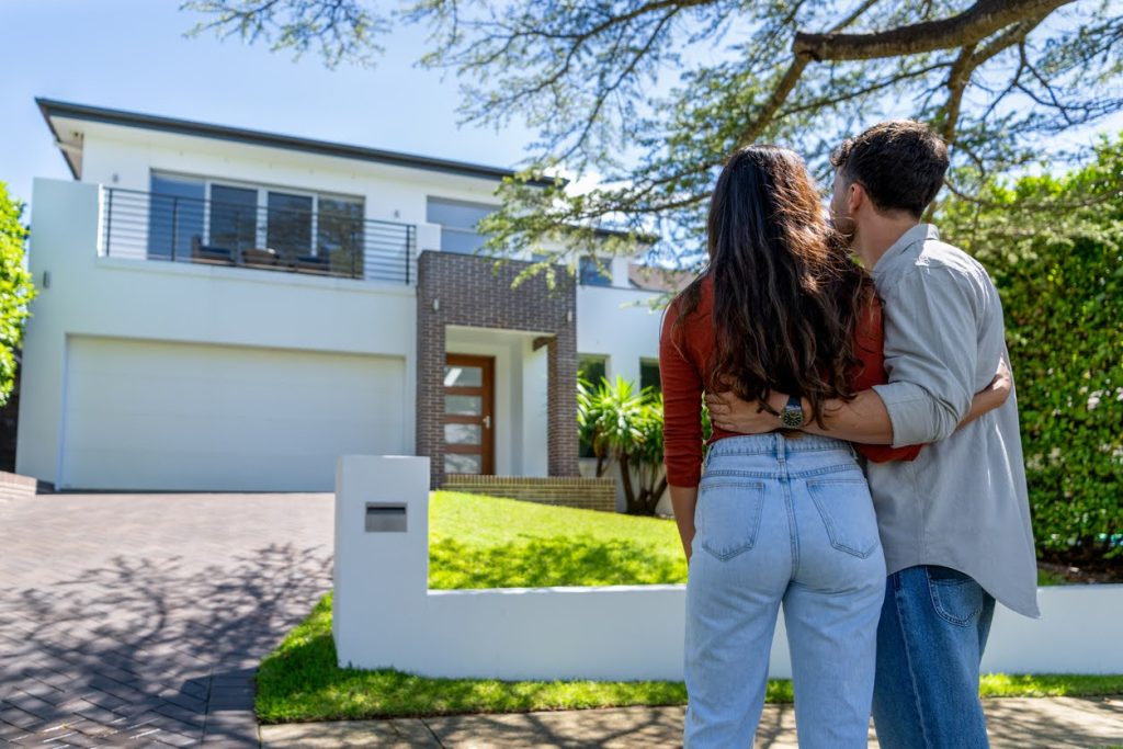 Couple admiring modern home exterior in Sydney, reflecting aspirations of home ownership and property investment.