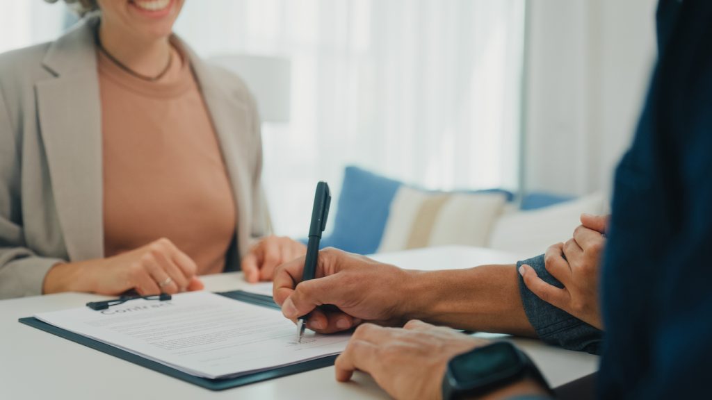 Client signing a document with a financial advisor in a professional setting, emphasising mortgage consultations and finance solutions.